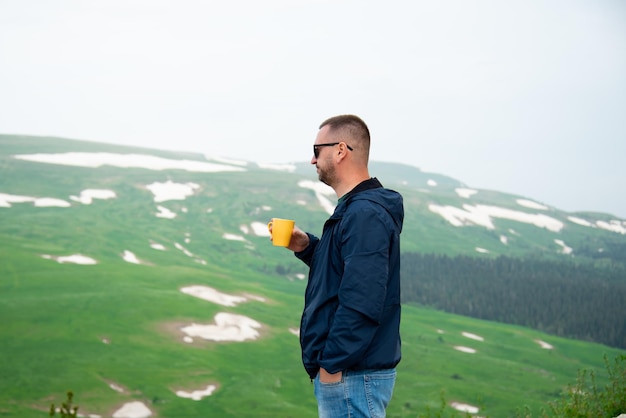 Een man met een gele mok kijkt naar een plateau in de bergen Vakantie