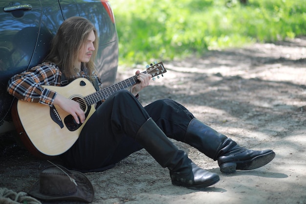 Een man met een gitaar op een hete zomerdag buiten