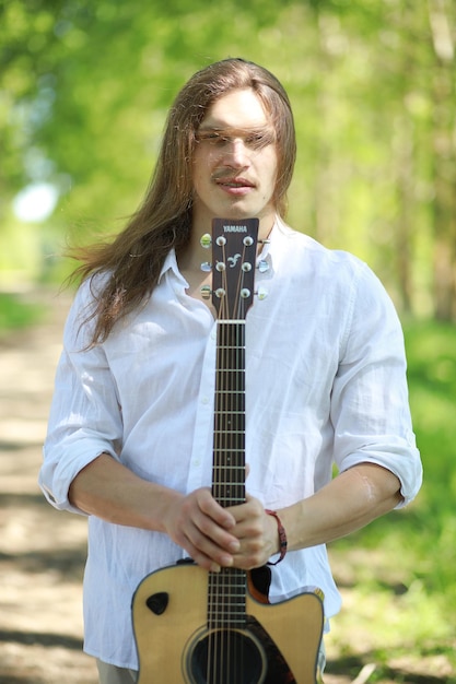 Een man met een gitaar op een zomerdag buiten