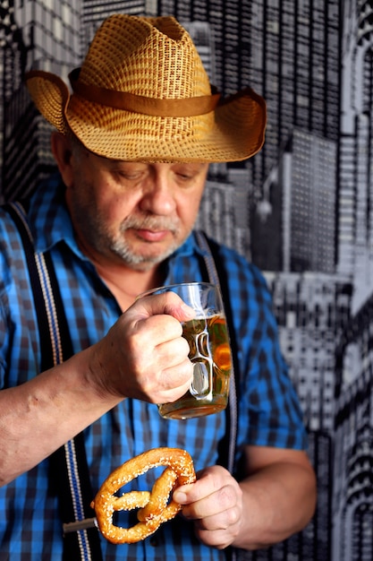 Een man met een glas bier en een krakeling. Oktoberfest-viering.