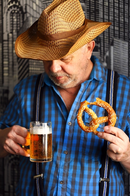 Een man met een glas bier en een krakeling. Oktoberfest-viering.