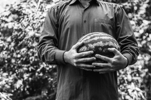 Een man met een grote rijpe watermeloen