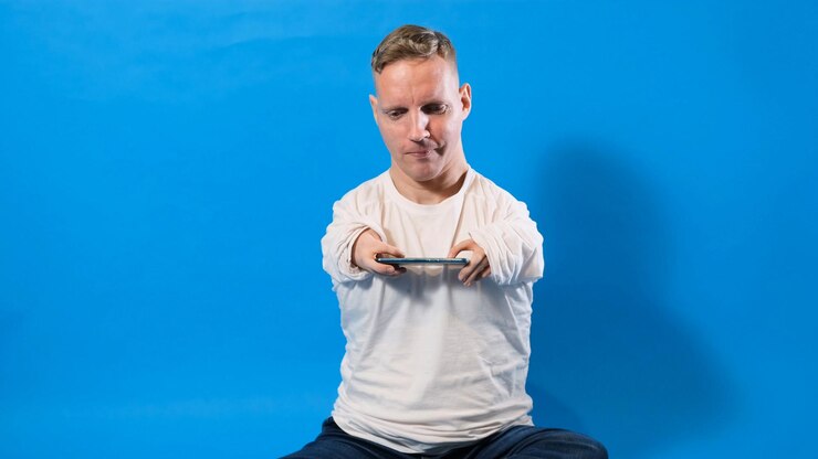 Een man met een handicap speelt een spel op een smartphone op een geïsoleerde achtergrond