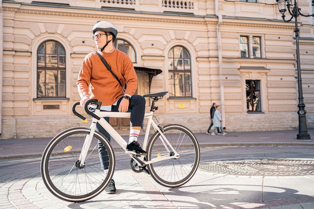 Een man met een helm rijdt op een fiets om stedelijk ecovervoer te werken