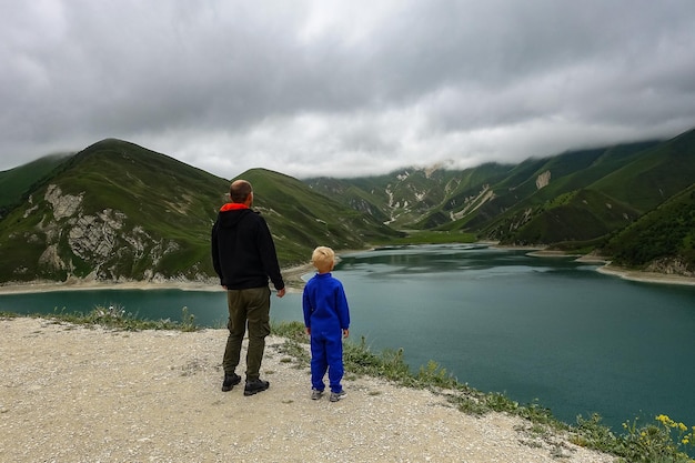 Een man met een kind op de achtergrond van het Kezenoyam-meer in de bergen van de Kaukasus in Tsjetsjenië, Rusland