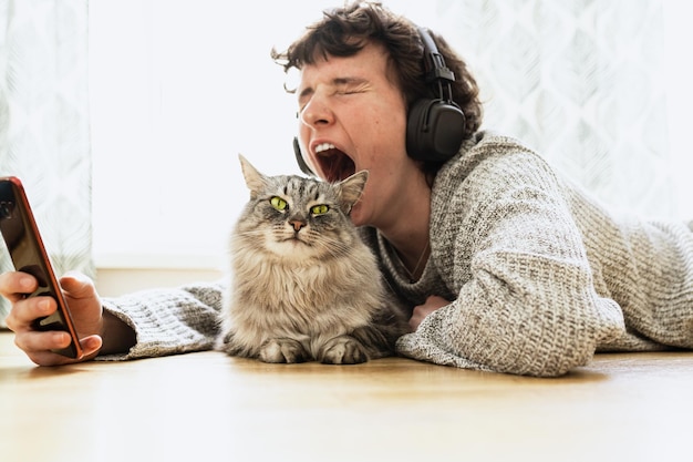 Een man met een koptelefoon op en een kat op de grond.