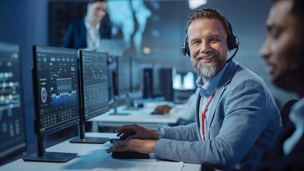 Foto een man met een koptelefoon zit aan een bureau met een monitor waarop een man met een koptelefoon te zien is.