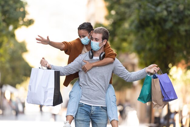 Een man met een meisje op de rug met weinig boodschappentassen en medische gezichtsmaskers