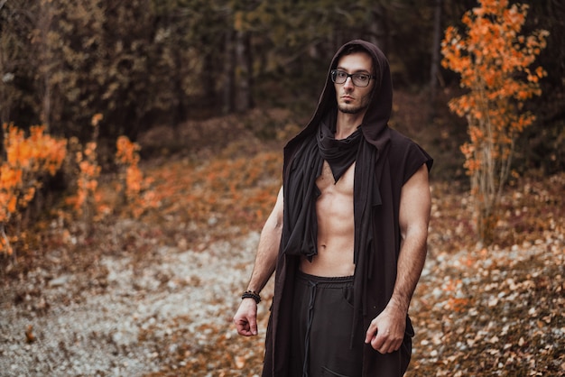 Een man met een naakt torso staat op het herfstbos