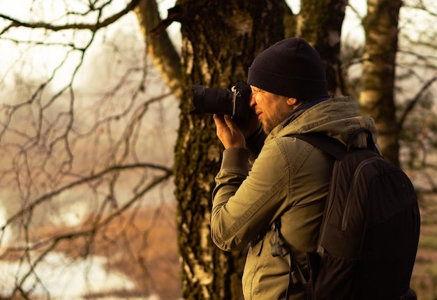 Een man met een professionele fotocamera en rugzak voor fotoaccessoires fotografeert de natuur op een zonnige dag