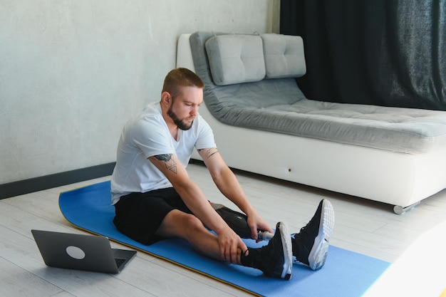 Een man met een prosthetisch been doet thuis sportoefeningen op een mat Het concept van rehabilitatie