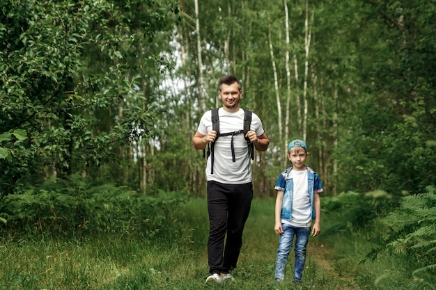 Een man met een rugzak, een vader en zijn zoon op een wandeling, wandelen tijdens boswandelingen.