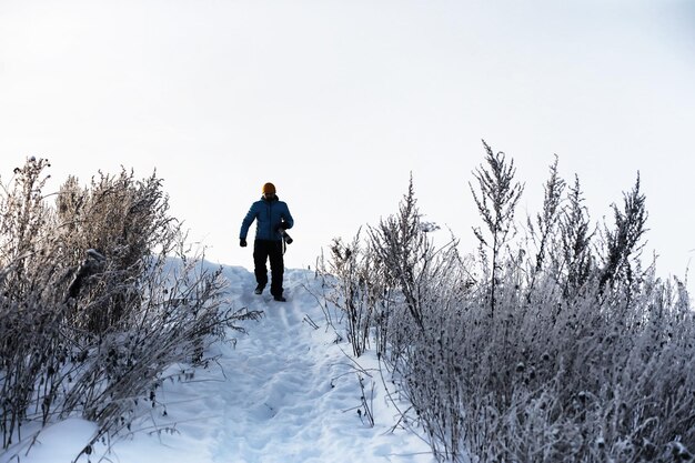 Een man met een rugzak reist in de winter Een man in een besneeuwd veld Wandelend winterlandschap