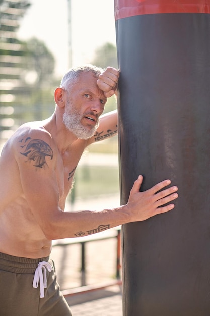 Een man met een tatoeage op een schouder die rust na een bokstraining