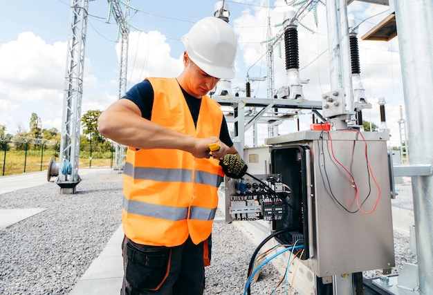 Een man met een veiligheidsvest aan werkt aan een elektriciteitskast.