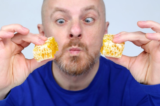 Een man met eetlust kijkt naar twee stukken honingraathoning in zijn handen