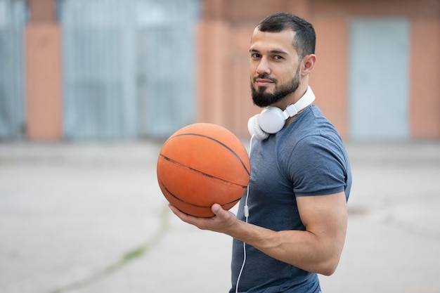 Foto een man met koptelefoon staat op straat met een basketbal in zijn handen