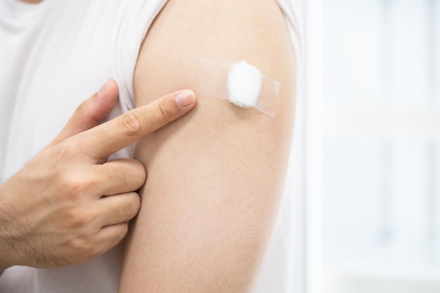 Een man met medische pleister op arm na covid 19-vaccin