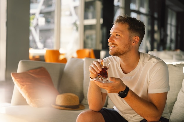 Een man met snor drinkt en geniet van Turkse traditionele hete thee in de lobby van een Turks hotel