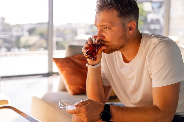 Een man met snor drinkt en geniet van Turkse traditionele hete thee in de lobby van een Turks hotel