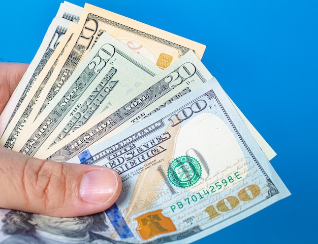 een man met waaiervormige Amerikaanse dollarbiljetten met blauwe achtergrond