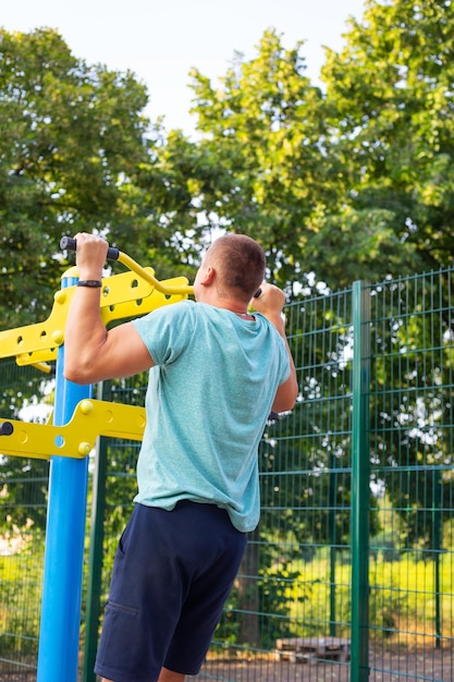 Een man oefent op straat Sportschool openen buiten op het sportveld in een groen park