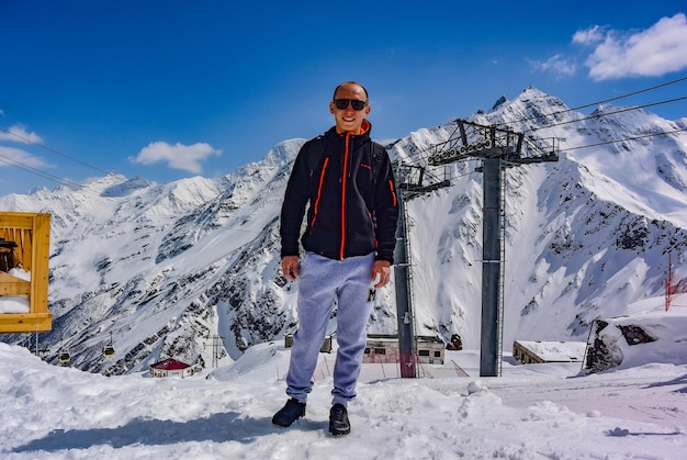 Foto een man op de achtergrond van een gondelkabelbaan en de besneeuwde bergen van elbrus 2019 rusland