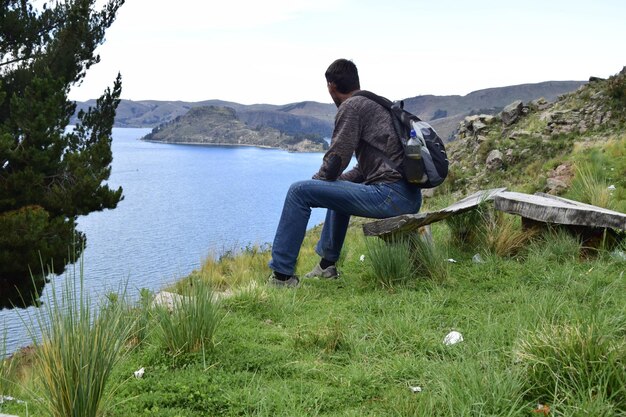 Een man op een bankje kijkt naar het landschap van het Titicacameer Copacabana Bolivia