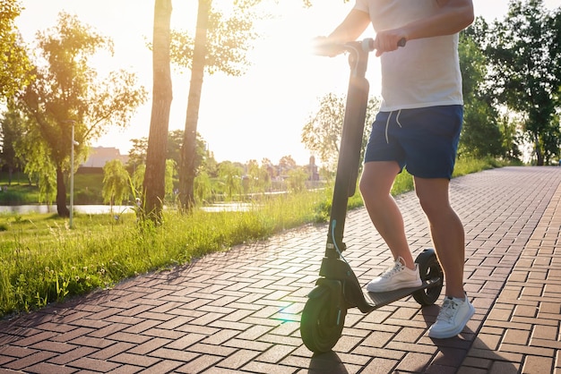 Een man op een moderne scooter op een parkweg op een zonnige dag ecologisch stadsvervoer