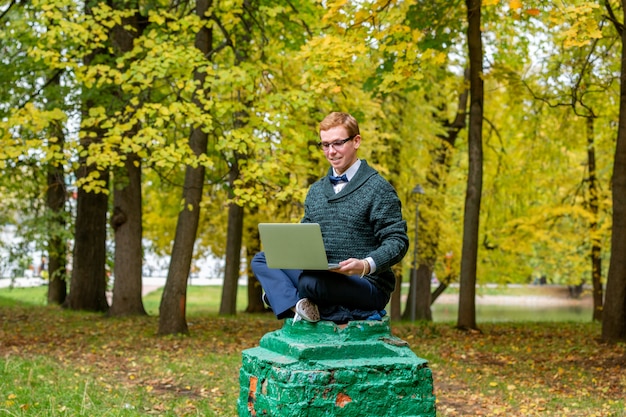 Een man op een voetstuk die zich voordoet als een standbeeld in het herfstpark.