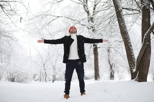 Een man op een wandeling in het park. Jonge man met een paraplu onder de wintersneeuwval.