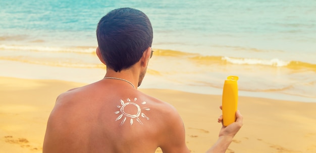 Een man op het strand met zonnebrandcrème op zijn rug