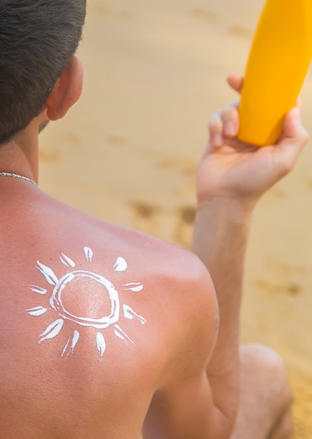 Foto een man op het strand met zonnebrandcrème op zijn rug