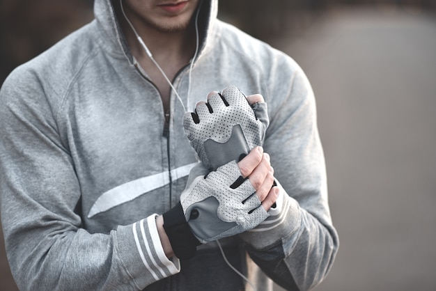 Een man op straat trekt zijn sporthandschoenen aan en bereidt zich voor op coaching.