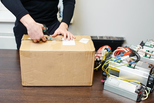 Een man pakt een doos met apparatuur uit om cryptocurrency bitcoin te minen