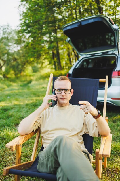 Een man praat op een smartphone terwijl hij op een bankje in een stadspark zit Een jonge man leest het nieuws en schrijft een bericht op zijn mobiele telefoon Recreatie in de natuur werken op afstand op vakantie