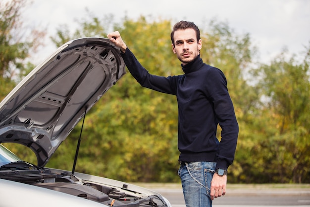 Een man probeert de auto onderweg te repareren