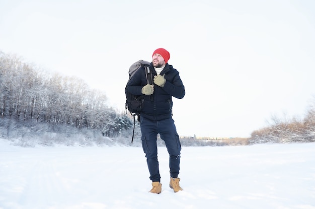 Een man reist met een rugzak. Winterwandeling in het bos. Toerist op een wandeling in de winter in het park.