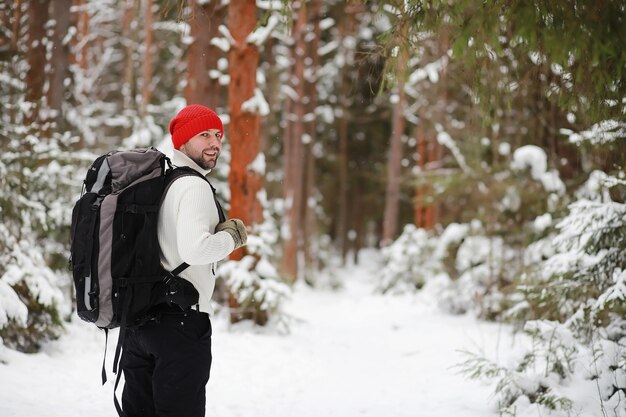 Een man reist met een rugzak. Winterwandeling in het bos. Toerist op een wandeling in de winter in het park.