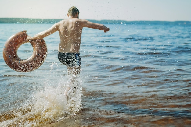 Een man rent door het water met een cirkel in zijn hand.