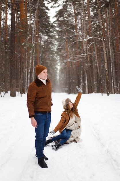 Een man rolt een meisje op een slee door een besneeuwd winterpark