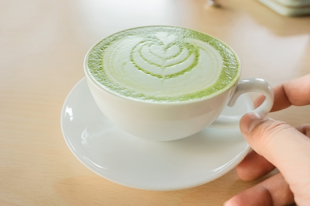 een man&#39;s hand met een hete matcha groene thee beker