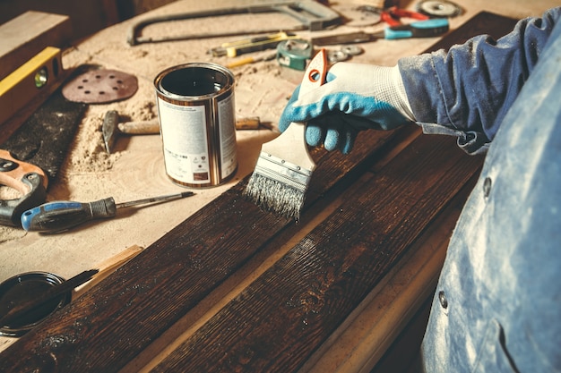 Foto een man schildert in een werkplaats een handgemaakt houten product met verf