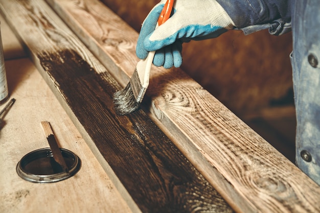 Een man schildert in een werkplaats een handgemaakt houten product met verf