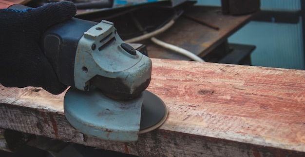 Een man schuurt een plank Oude verf van planken verwijderen Timmerwerk