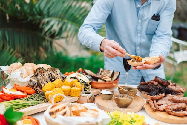 Een man serveert eten aan een picknicktafel.
