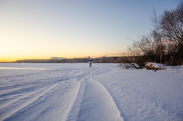 Foto een man skiet op een bevroren meer met een zonsondergang op de achtergrond