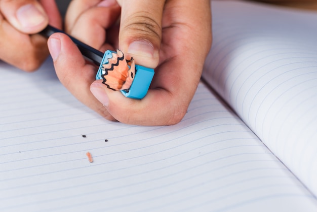 Foto een man slijpen potlood op witte lijnen papier boekpagina