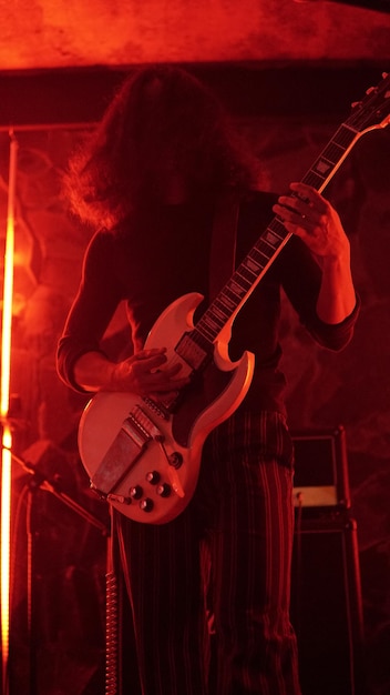 Foto een man speelt gitaar in een rood licht.