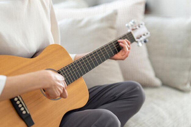 een man speelt gitaar met een witte bank achter hem